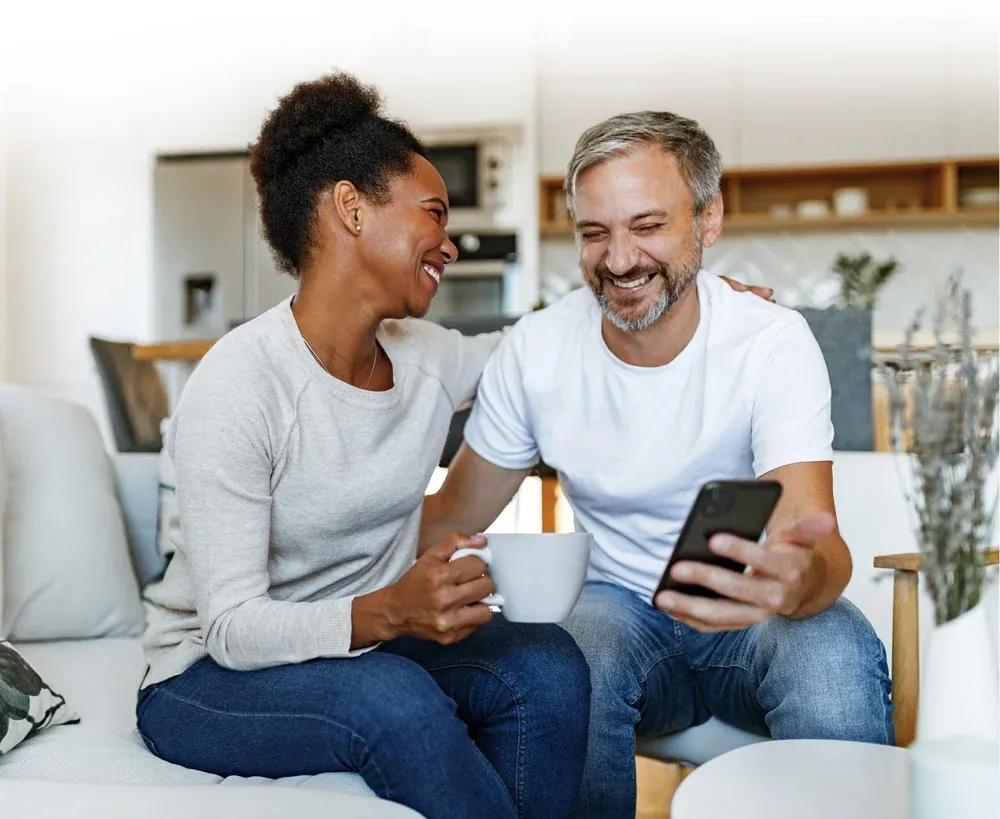 Couple on a sofa using a free Lifeline phone and a tablet